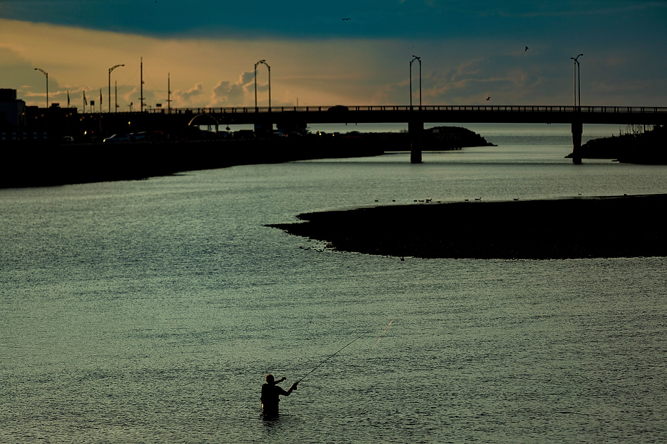 Un homme pêche dans la rivière Matane, aux abords du pont de l’avenue du Phare
