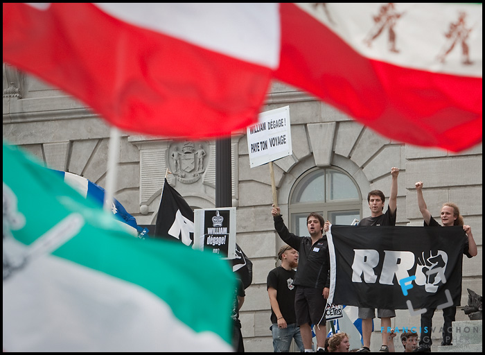 Protesters wave flag and sign at the door of the Quebec National Assembly as they demonstrate against the the royal visit  by Britain's Duke and Duchess of Cambridge, Prince William and Kate Middleton, during a demonstration organized by the pro-independence group Réseau de Résistance du Québecois  in Quebec City Sunday July 3, 2011.