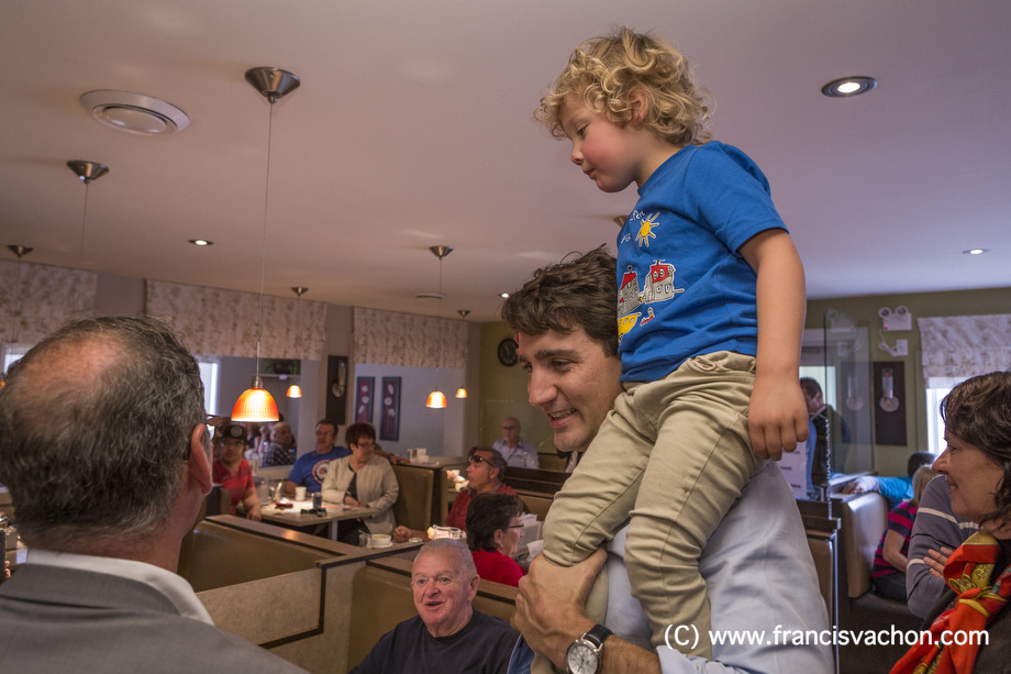Justin Trudeau shakes hands in a restaurant as his son Hadrien, 3, sits on his shoulder in Roberval, Qc, on Thursday October 19, 2017. THE CANADIAN PRESS/Francis Vachon.