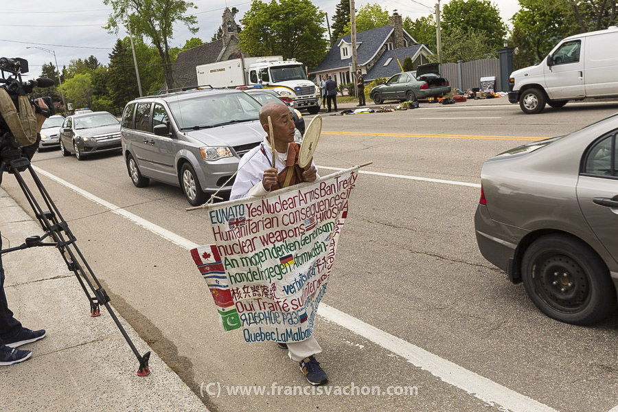 Le manifestant antinucléaire Toyoshige Sekiguchi passe devant un véhicule suspect à La Malbaie après une marche depuis Montréal, le 7 juin 2018.