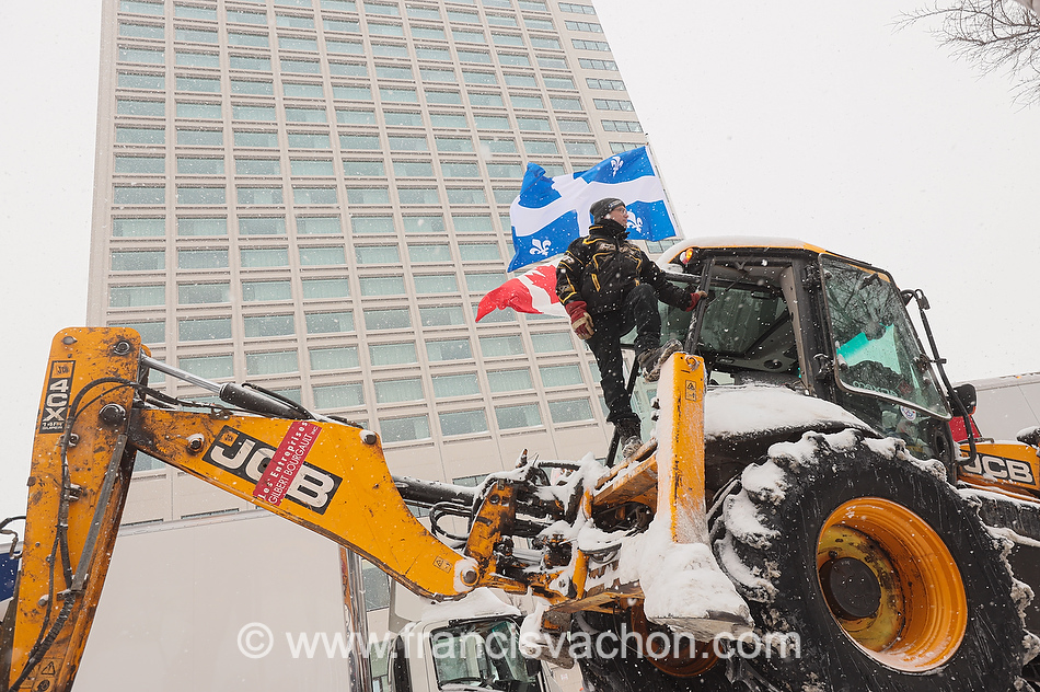 Un homme regarde la foule, juché sur son tracteur, pendant la manifestation du 19 et 20 février à Québec