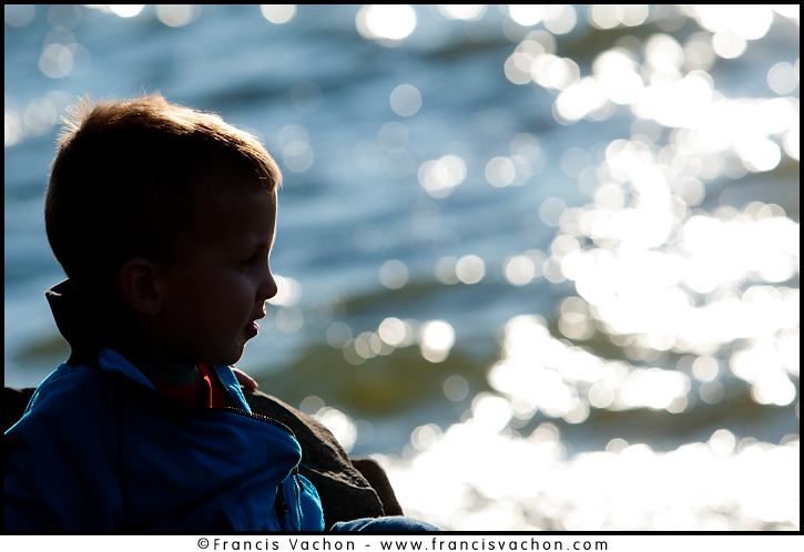 Kid looking at a river at sunset